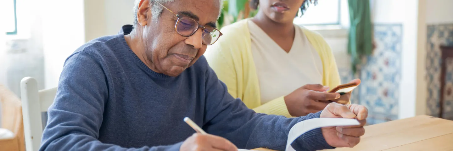 Man at a table completing a form with woman beside him