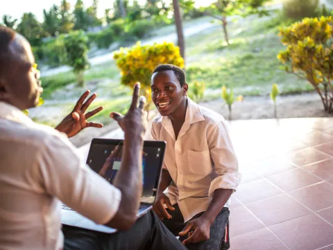 Two male colleagues talking with laptop