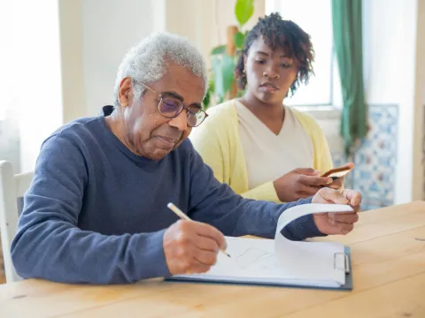 Man at a table completing a form with woman beside him